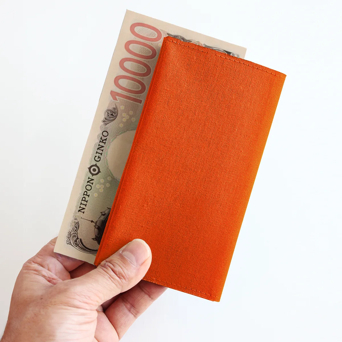 Tyla長財布オレンジと一万円札を持っている手