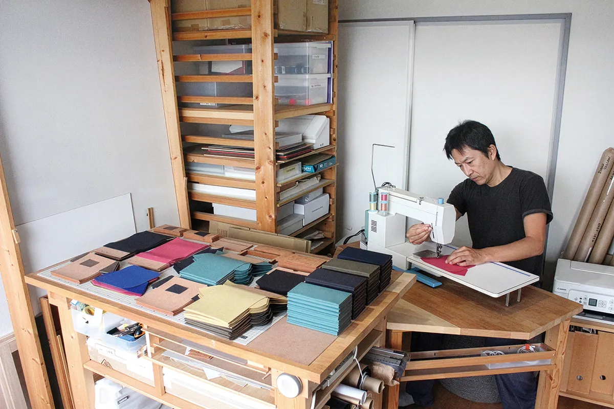 Tyla長財布を作業場で作っている人と作業台の上に並ぶ素材